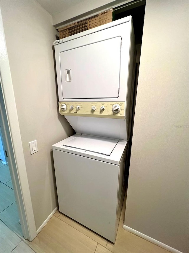 laundry room with light hardwood / wood-style floors and stacked washer / drying machine