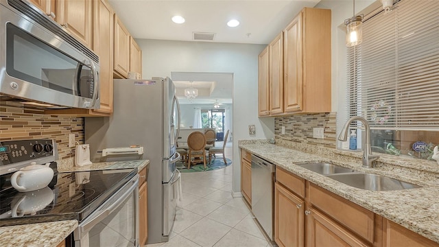 kitchen with sink, backsplash, stainless steel appliances, and light stone countertops