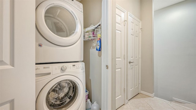 washroom featuring stacked washer and clothes dryer and light tile floors