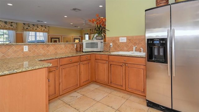 kitchen featuring light stone counters, stainless steel refrigerator with ice dispenser, backsplash, sink, and light tile floors