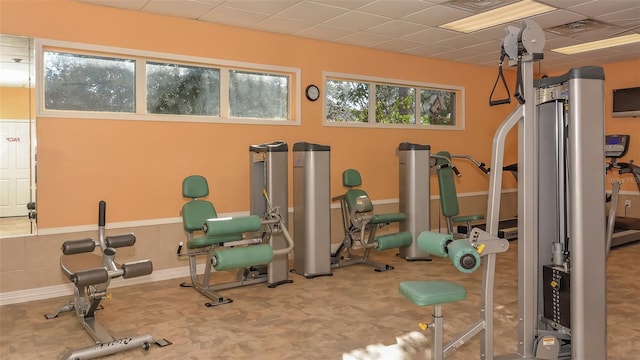 exercise room with a paneled ceiling and carpet flooring