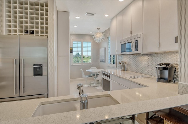 kitchen with sink, backsplash, stainless steel appliances, and light stone countertops