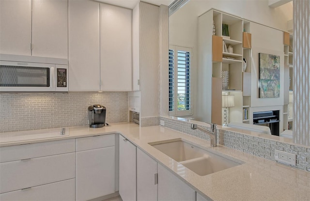 kitchen featuring white cabinets, sink, backsplash, and light stone counters