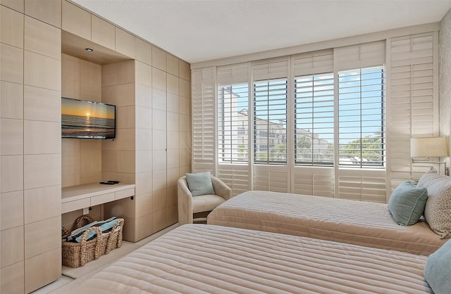 bedroom with multiple windows, tile walls, built in desk, and carpet flooring