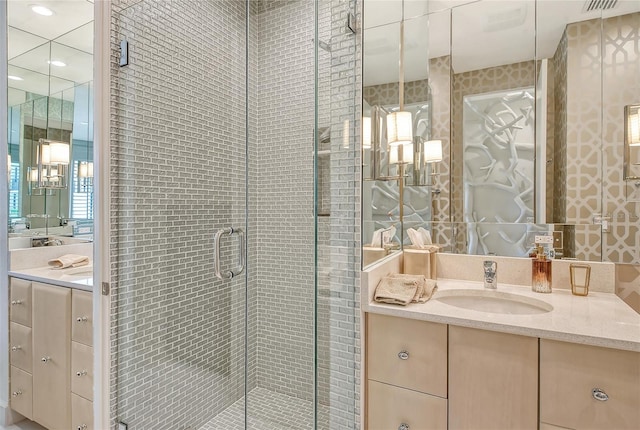 bathroom featuring a shower with shower door and vanity with extensive cabinet space