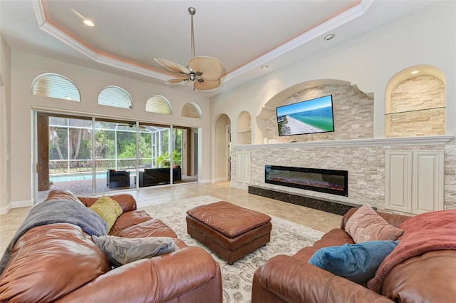 living room with ceiling fan, light tile patterned flooring, a fireplace, and a tray ceiling