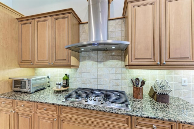 kitchen featuring stainless steel gas stovetop, ventilation hood, tasteful backsplash, and stone countertops