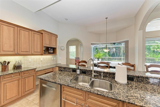 kitchen with dishwasher, dark stone counters, sink, and hanging light fixtures