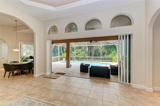 interior space with ceiling fan, light tile patterned floors, ornamental molding, and a raised ceiling