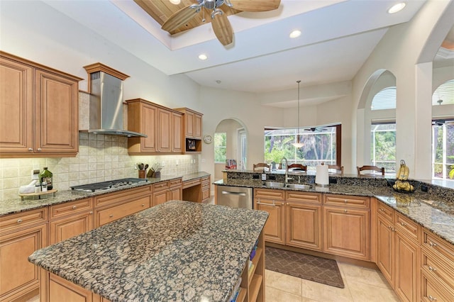 kitchen with backsplash, appliances with stainless steel finishes, wall chimney range hood, and dark stone countertops