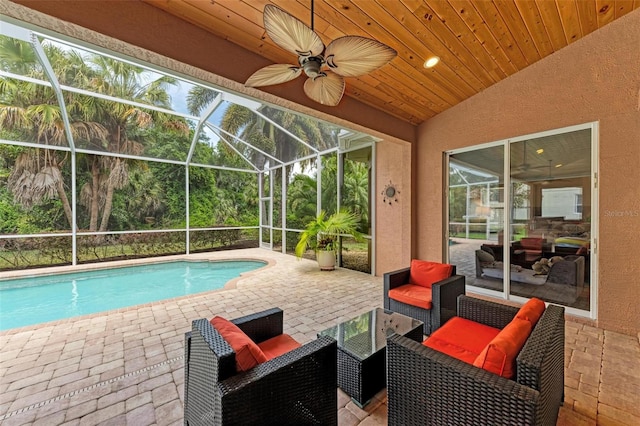 view of swimming pool with ceiling fan, an outdoor hangout area, a patio, and glass enclosure