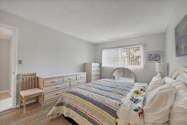 bedroom with a textured ceiling and light hardwood / wood-style floors