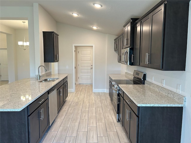 kitchen featuring light stone counters, appliances with stainless steel finishes, vaulted ceiling, a sink, and a chandelier