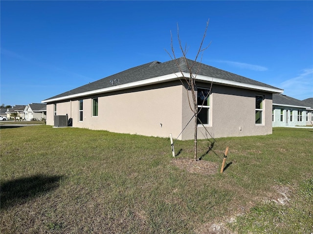 view of side of home with central air condition unit, stucco siding, and a yard