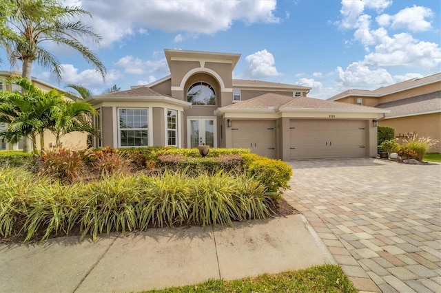 mediterranean / spanish house with french doors, decorative driveway, a garage, and stucco siding