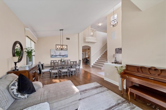 living room featuring dark hardwood / wood-style floors, lofted ceiling, and an inviting chandelier