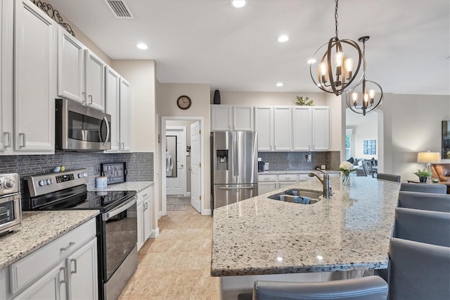 kitchen with white cabinets, sink, a breakfast bar area, a notable chandelier, and stainless steel appliances