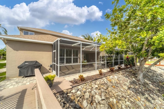 rear view of property with glass enclosure and a patio area