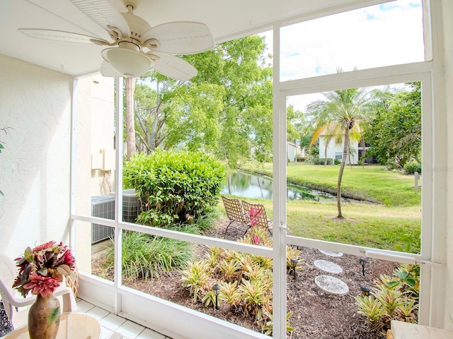 sunroom / solarium with ceiling fan and a water view