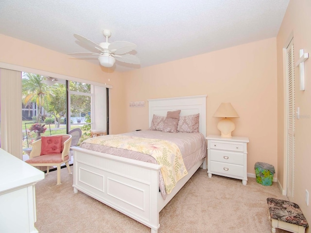 carpeted bedroom featuring ceiling fan and a textured ceiling