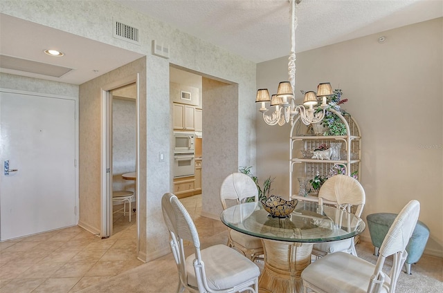 tiled dining area featuring a textured ceiling and an inviting chandelier