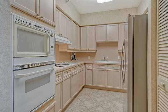 kitchen with sink, white appliances, light tile floors, and light brown cabinets