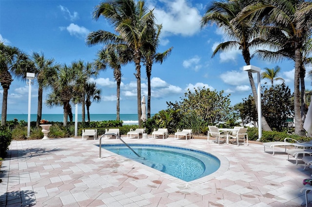 view of pool with a water view and a patio area