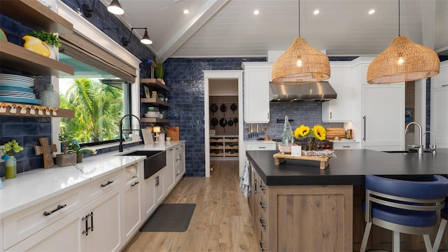 kitchen with light wood-type flooring, sink, beam ceiling, white cabinets, and range hood