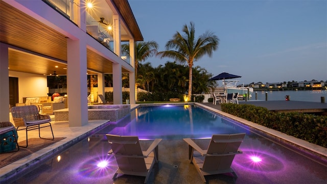 pool at dusk featuring ceiling fan, an outdoor hangout area, a patio area, an in ground hot tub, and a water view