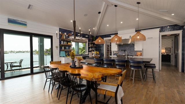 dining space with lofted ceiling with beams, a water view, hardwood / wood-style flooring, and wood ceiling