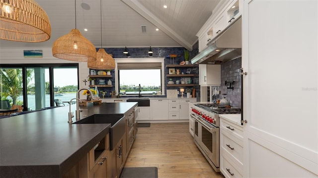 kitchen with double oven range, sink, beamed ceiling, decorative light fixtures, and white cabinetry