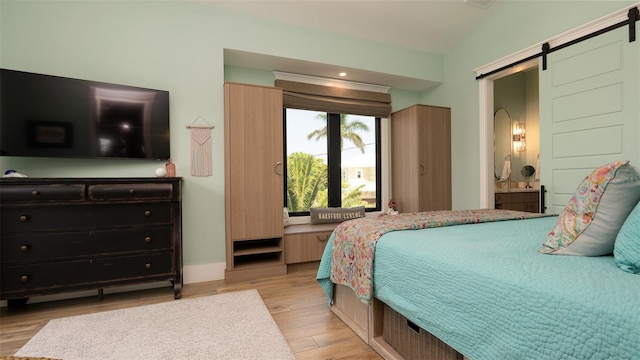 bedroom featuring a barn door and light hardwood / wood-style flooring