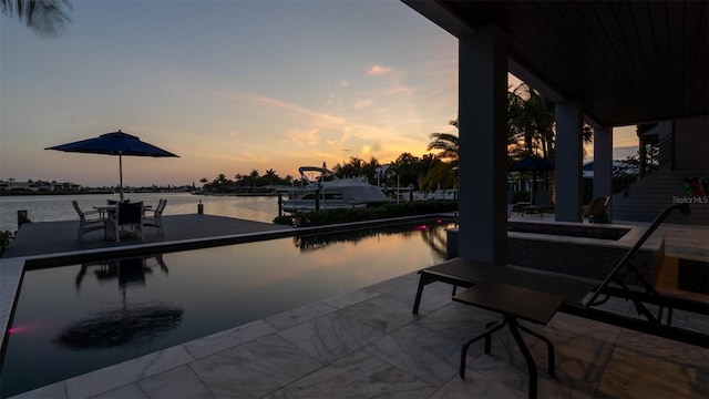 pool at dusk featuring a water view