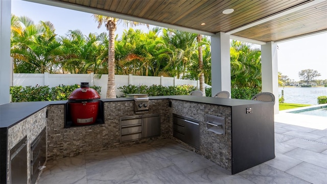 view of patio / terrace with a pool, an outdoor kitchen, a water view, and area for grilling