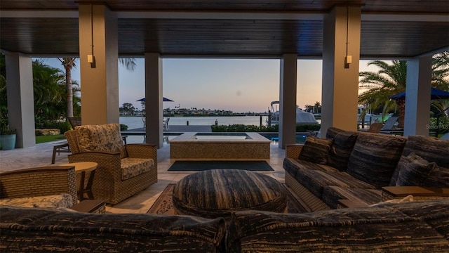 patio terrace at dusk featuring outdoor lounge area and a water view