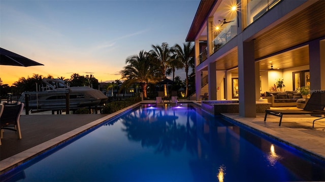 pool at dusk featuring outdoor lounge area, ceiling fan, a patio, and a hot tub