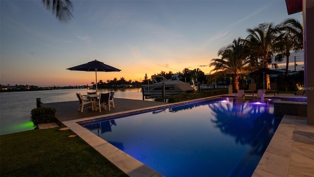 pool at dusk with a water view and a patio