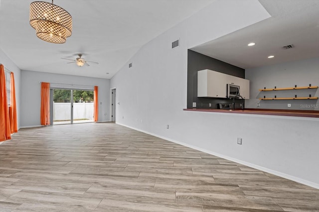 unfurnished living room featuring vaulted ceiling, ceiling fan, and light wood-type flooring