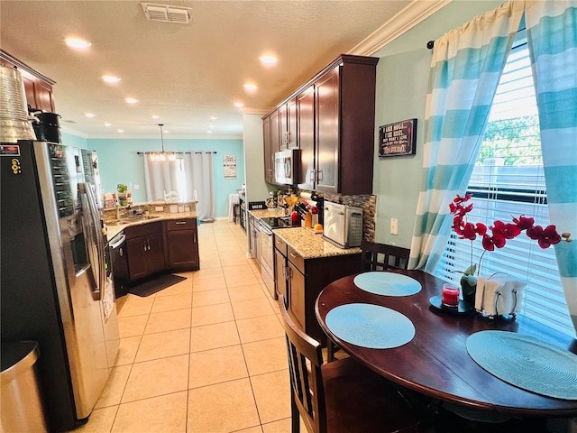 kitchen with appliances with stainless steel finishes, light tile floors, decorative light fixtures, ornamental molding, and light stone countertops