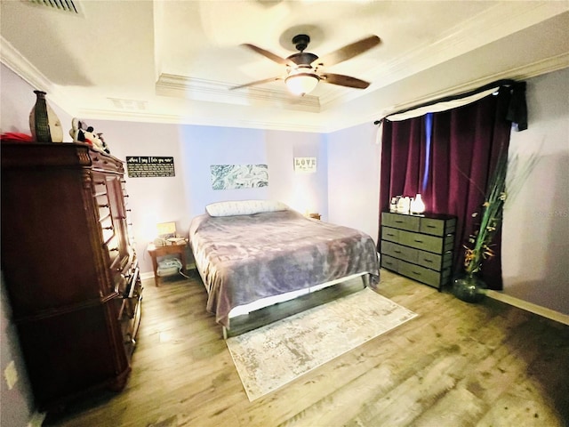 bedroom featuring light hardwood / wood-style flooring, a raised ceiling, ceiling fan, and ornamental molding