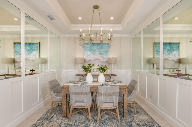 dining area with light tile patterned floors, an inviting chandelier, a raised ceiling, and ornamental molding