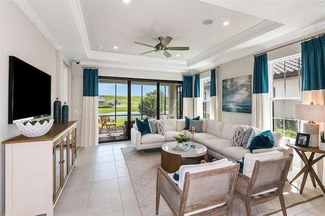 living room featuring a tray ceiling, ceiling fan, light tile patterned flooring, and ornamental molding