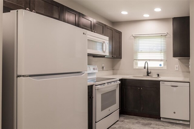 kitchen featuring dark brown cabinetry, sink, white appliances, and light hardwood / wood-style floors