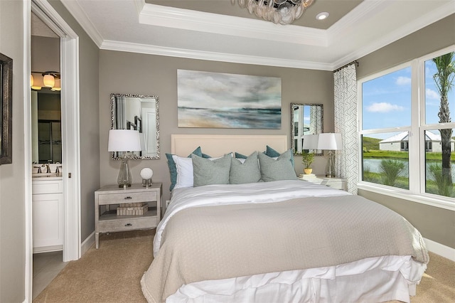 carpeted bedroom with a water view, ornamental molding, connected bathroom, and a tray ceiling