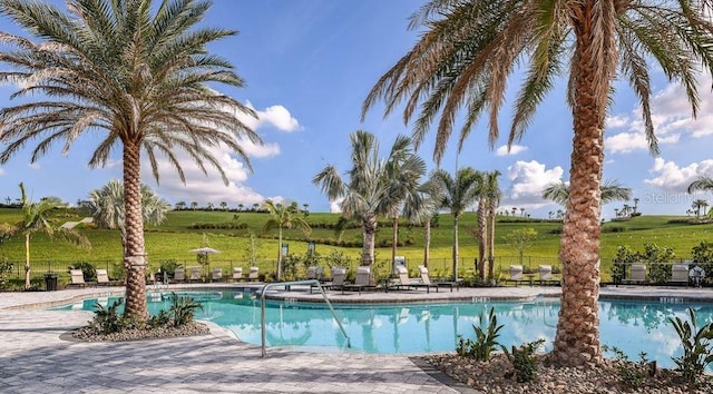 view of swimming pool with a patio area and a rural view