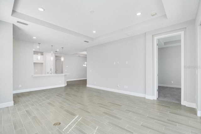 unfurnished living room featuring a raised ceiling and sink