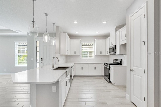 kitchen featuring appliances with stainless steel finishes, tasteful backsplash, hanging light fixtures, sink, and white cabinetry