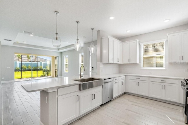 kitchen with appliances with stainless steel finishes, sink, white cabinetry, decorative light fixtures, and kitchen peninsula