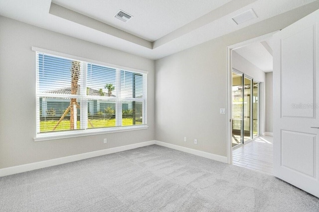 carpeted spare room with a tray ceiling