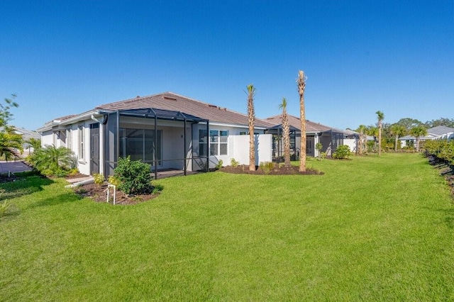 back of property featuring glass enclosure and a lawn